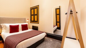 Ein Hotelzimmer mit einem Bett, einem Spiegel, einer Holzleiter und einer Tür mit Fenster.
