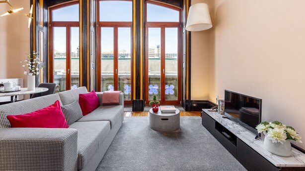 Ein modernes Wohnzimmer mit einer Couch, Couchtisch, Fernseher und großen Fenstern mit Blick.