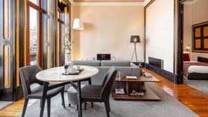 Ein modernes Hotelzimmer mit einem runden Esstisch, zwei Stühlen, einer Couch, einem Fernseher und einem Bett.