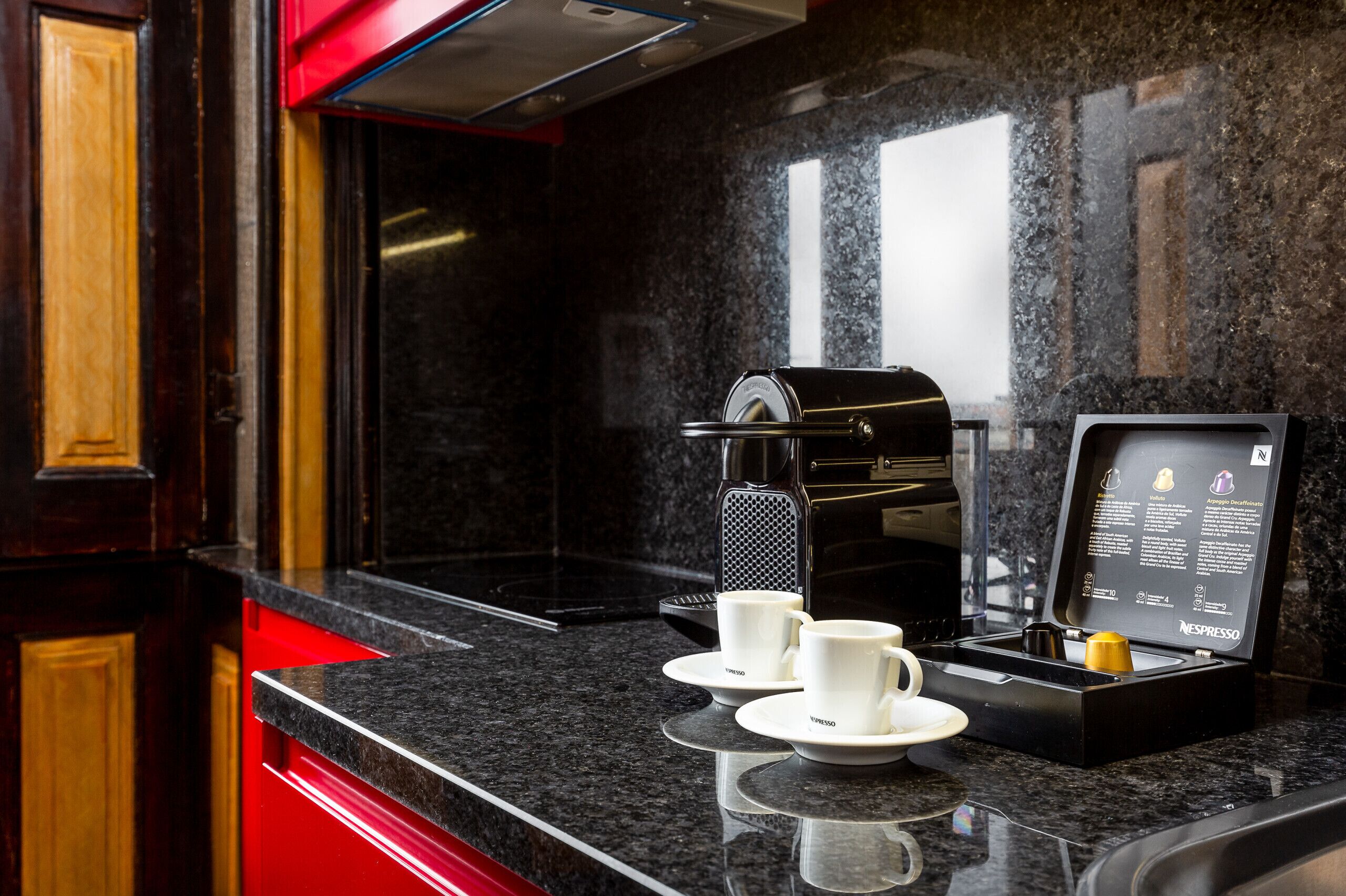 A modern kitchen with a coffee machine, two white cups, and a digital menu display.