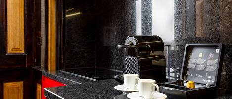 A modern kitchen with a coffee machine, two white cups, and a digital menu display.