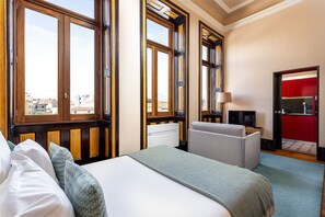 A hotel room with a large bed, a desk with a chair, a TV, and a red door. - Authentic Studio in Bolhão Market (Oporto)