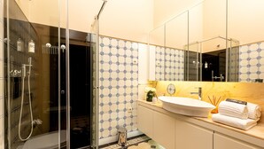 A modern bathroom with a glass-enclosed shower, a white sink, and a mirror above it. - Authentic Studio in Bolhão Market (Oporto)