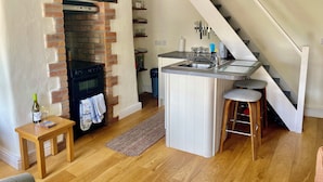 A kitchen with a brick wall, wooden table, and a small island with a sink.