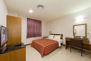 Une chambre d’hôtel équipée d’un lit, d’un bureau, d’une chaise, d’une télévision et d’un miroir.