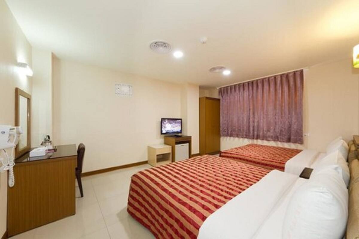 Une chambre d’hôtel avec deux lits, un bureau avec une chaise, une télévision et une salle de bain.