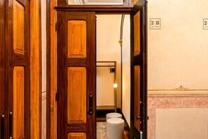A wooden door leading to a hallway with a mirror and a sign indicating '2-B Apartment'.