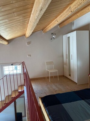 A bedroom with a wooden ceiling, a bed, a wardrobe, a chair, and a window. -  "Little cottage
 surrounded by olive and almond trees (Noto)