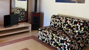 A living room with a red staircase, a black sofa with a polka dot cover, a television, and a wood-burning stove. -  "Little cottage
 surrounded by olive and almond trees (Noto)