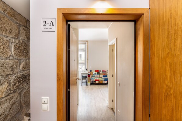 Een gang die leidt naar een kamer met een houten deurkozijn en een bordje met daarop '2-A Appartement'.