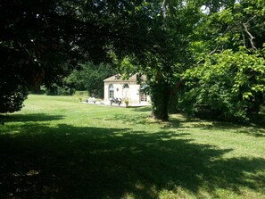 Escape to a serene courtyard surrounded by lush greenery and a charming stone-built guesthouse.