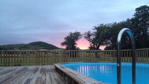 A wooden deck surrounding a swimming pool with a metal ladder.