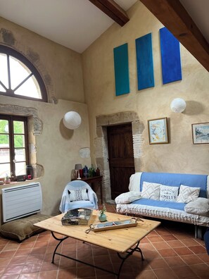 Una habitación acogedora con una mesa de madera, un sofá azul y una chimenea de piedra.