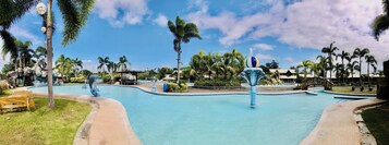 Piscina con fuente, rodeada de palmeras y cielo despejado.