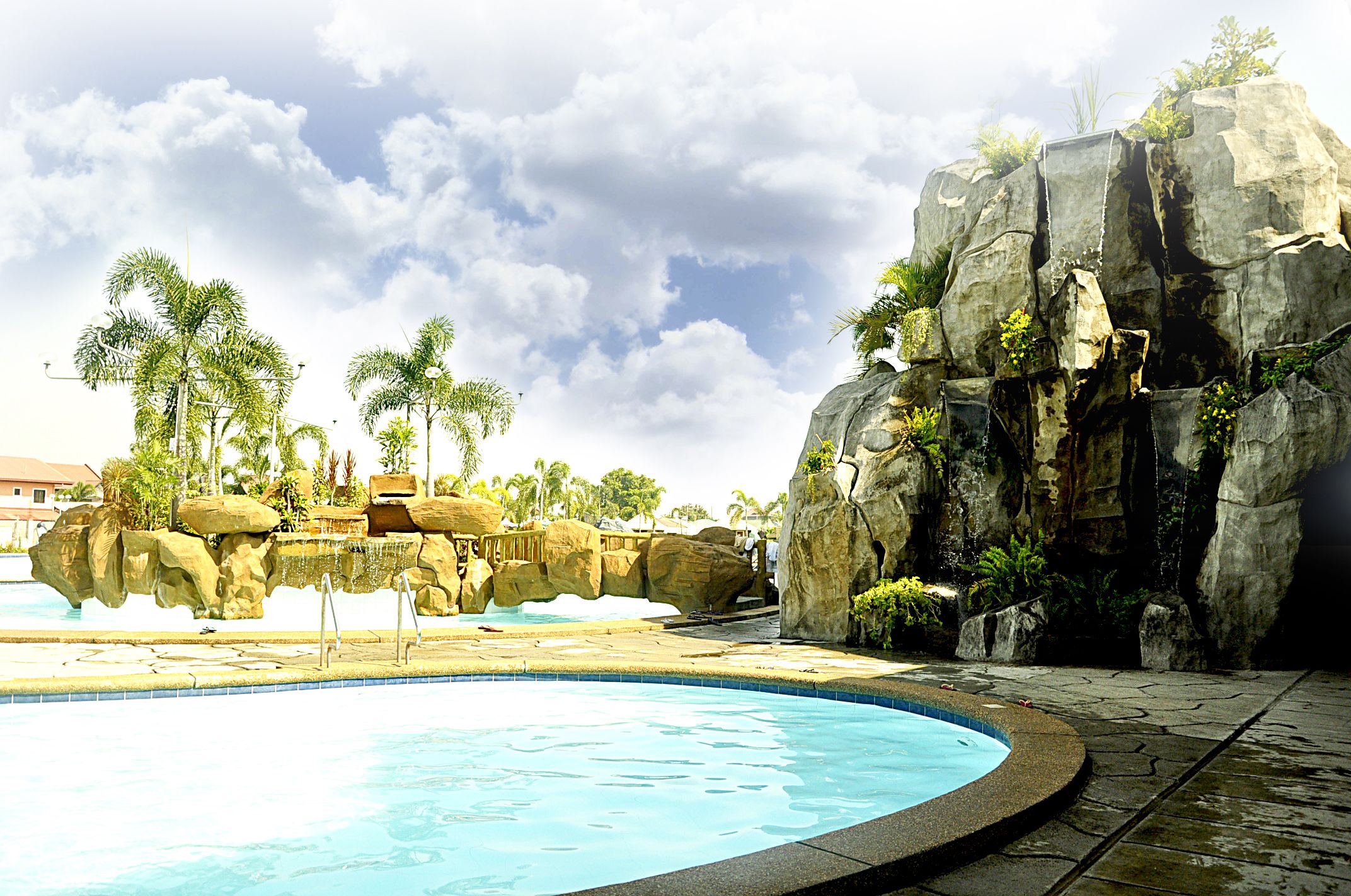 A swimming pool with rock formations and palm trees.
