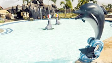 Uma estátua de golfinho em uma piscina, com um cenário de pedras e palmeiras.