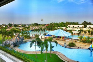 A resort with a large swimming pool, palm trees, and beach umbrellas. - Klir Waterpark Resort (Plaridel)