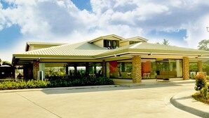 A modern building with a covered entrance, large windows, and a landscaped garden area.