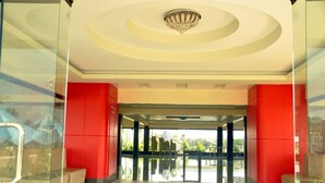 A modern lobby with a glass entrance, red pillars, and a chandelier.