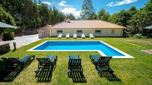 A house with a swimming pool, surrounded by green grass and trees. - Casa do Pioledo (Camélias de Basto-Turismo Rural) (Celorico de Basto)
