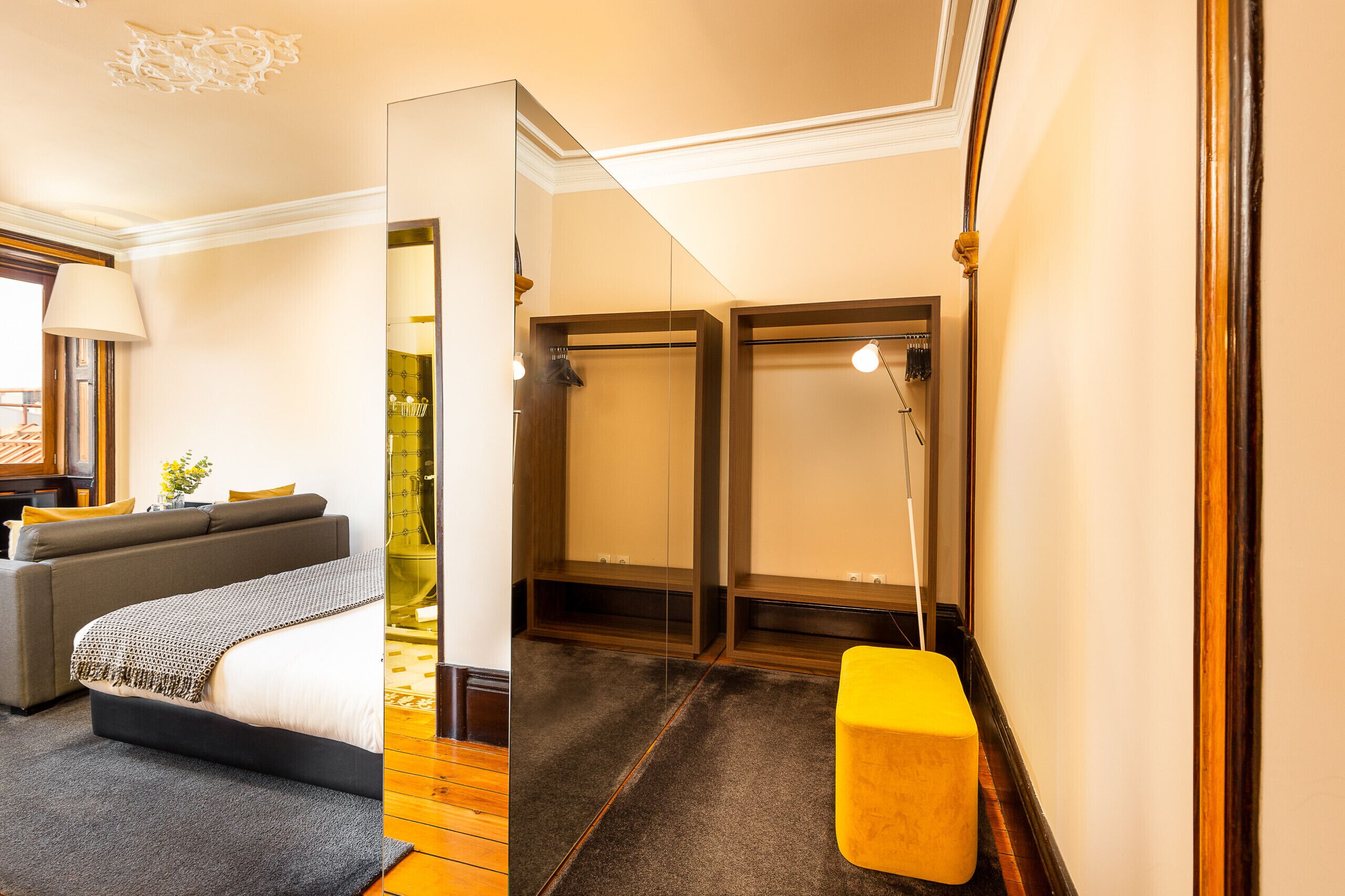 A hotel room with a bed, a sofa, a small table, and a bathroom with a shower.