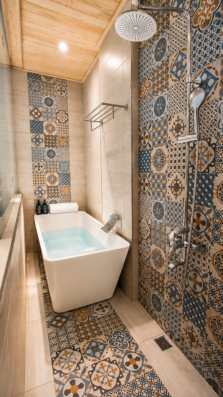 A bathroom with a freestanding bathtub, a shower with a rain showerhead, and patterned tiles on the walls and floor.