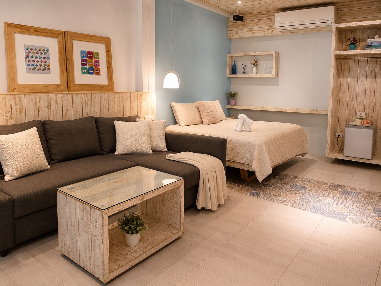 Un dormitorio moderno con sofá, dos camas, una mesita de centro y un televisor pequeño.
