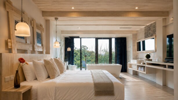 A modern bedroom with a large bed, a built-in TV, a bathtub, and a balcony with a view. - Azure Inn (Hengchun)