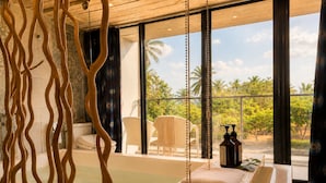 A spa room with a bathtub, a chair, and a view of palm trees. - Azure Inn (Hengchun)