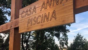 Un letrero de madera que indica 'CASA ANNA PISCINA', señalando un área de piscina.