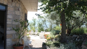 Un edificio de piedra con un patio de grava, una planta en maceta y mobiliario exterior.