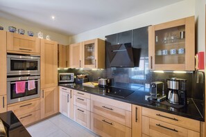 A modern kitchen with wooden cabinets, stainless steel appliances, and a black countertop.