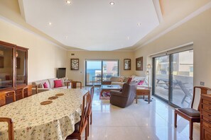 A spacious living area with a dining table, sofas, and a view to the outside.