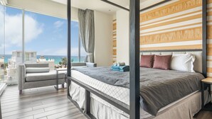 Une chambre moderne avec un grand lit, une vue sur l’océan et un balcon équipé d’un canapé.