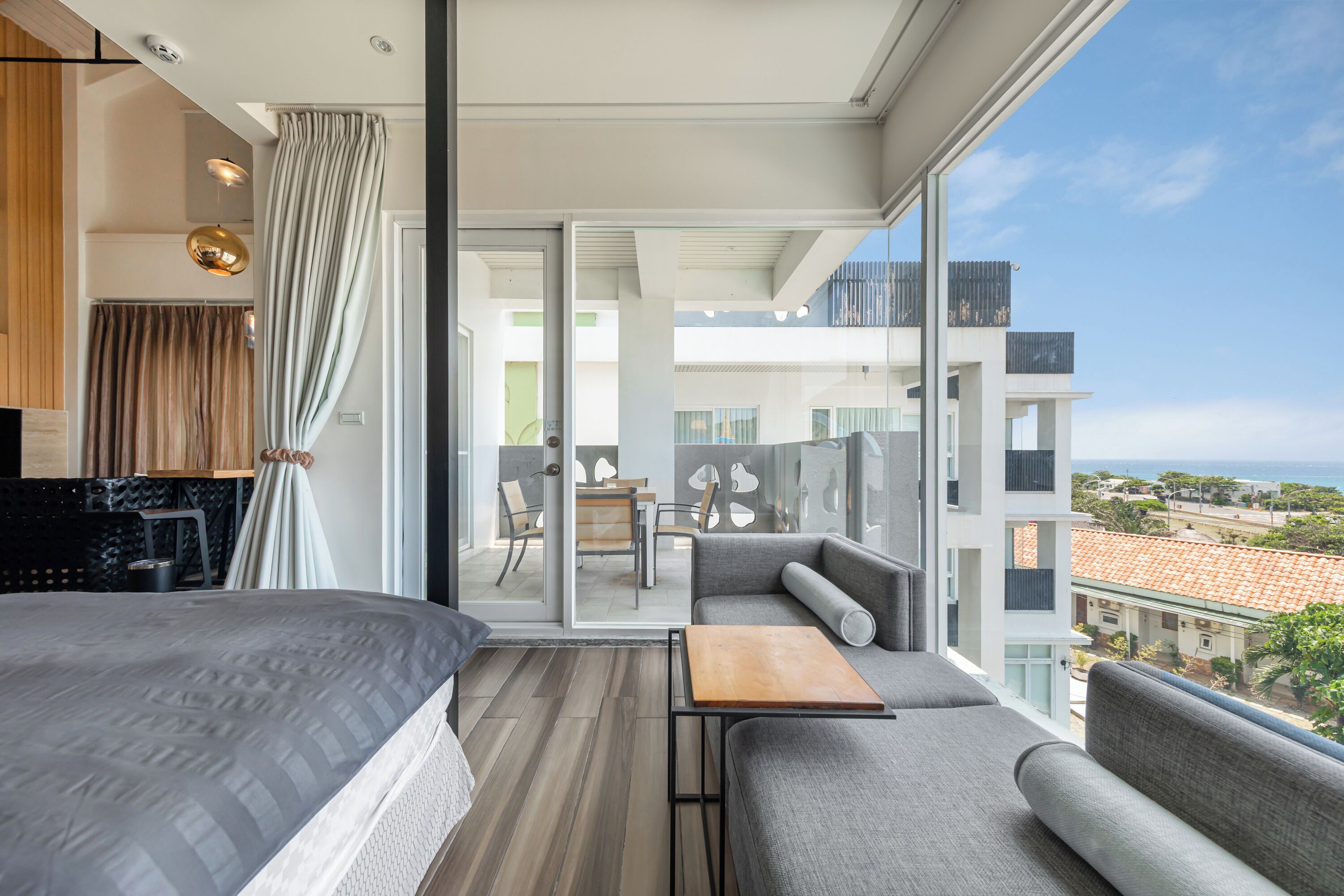 Una habitación de hotel moderna con balcón, sofá, una mesita y cama.