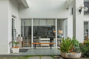 A modern house with a glass door entrance, a bench outside, and potted plants. - Zen Pin Inn (Hengchun)