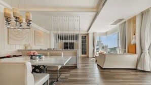 Une chambre d’hôtel moderne dotée d’un coin repas, d’un canapé et d’une grande fenêtre donnant sur la ville.