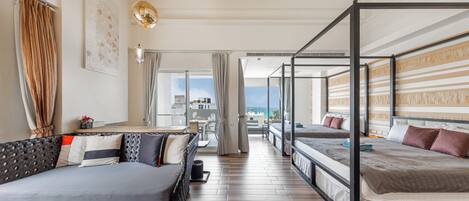 A modern hotel room with a large bed, a sofa, and a balcony with a view.