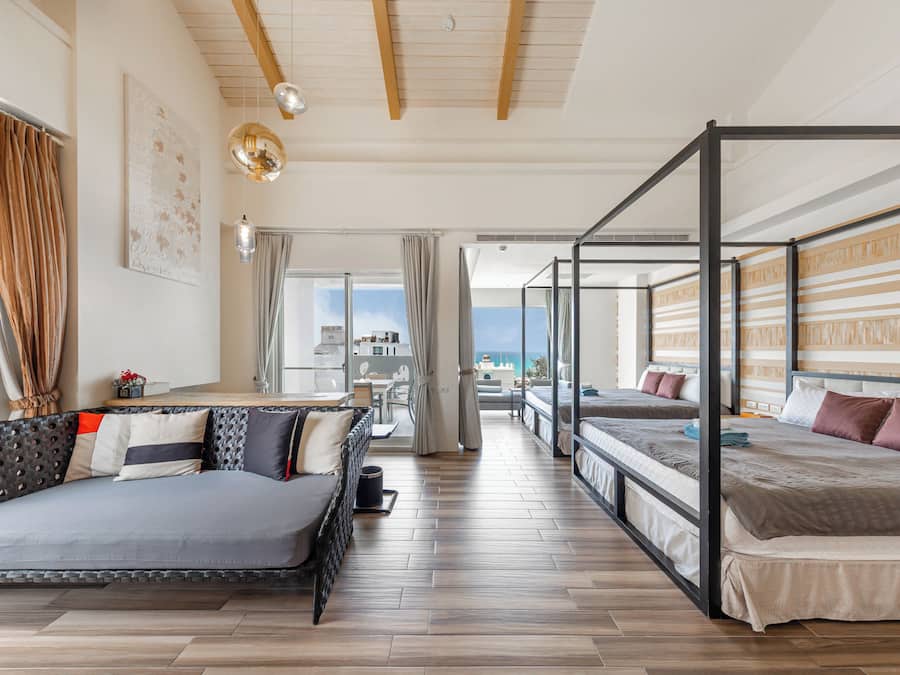 Habitación de hotel moderna con una cama grande, un sofá y un balcón con vistas.