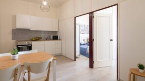 Una cucina moderna con mobili bianchi, un piano di lavoro in granito e un'area pranzo con tavolo e sedie in legno.