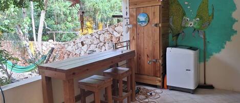 Cocina con barra de madera, refrigerador y vista a un jardín con hamaca.