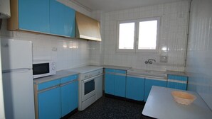 Une cuisine avec des meubles bleus, un réfrigérateur blanc, un four à micro-ondes et un évier.