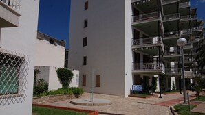 Un immeuble résidentiel à plusieurs étages, doté de balcons, d’une cour pavée et d’un lampadaire.