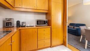 A compact kitchen with wooden cabinets, a microwave, a coffee maker, and a toaster.