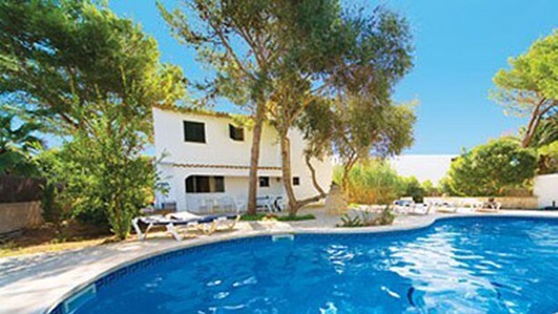 A swimming pool with lounge chairs and a white building in the background. - Lovely holiday villa. Pool and beach (Cala Serena)