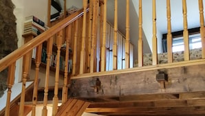 Eine Holztreppe mit einer Steinmauer an einer Seite und einem Sofa im unteren Bereich.