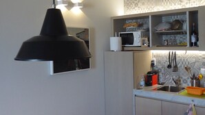Una cocina compacta con microondas, un lavabo y una toalla colgando.