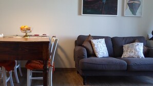 Una sala de estar con una mesa de comedor, sillas, un sofá y dos cuadros colgados en la pared.