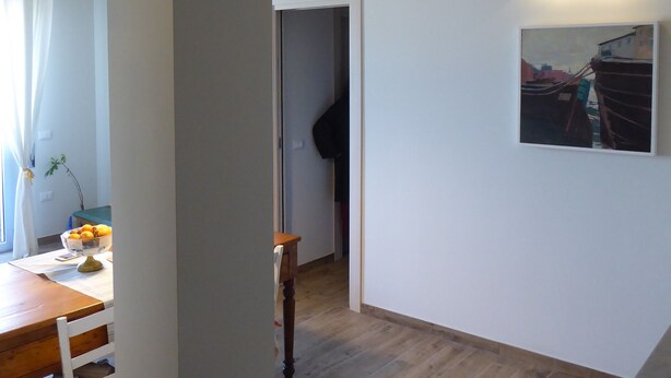 Un interior moderno con piso de madera, un comedor con mesa y sillas, y un pasillo que conduce a otra habitación.