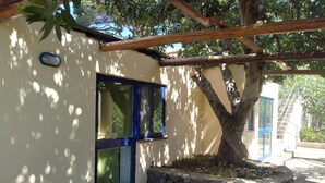 Un bâtiment avec un mur en pierre, une porte bleue et un arbre devant.